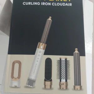 Silky Planet Curling Iron Cloudair - Multifunktionellt stylingverktyg från Silky Planet i vitt och guld med flera utbytbara borst- och locktillbehör. Perfekt för att skapa lockar, volym eller rakt hår. Modern design med digitala knappar och metalliska detaljer.