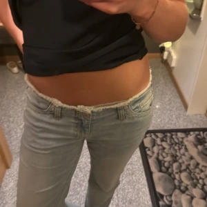 Ljusblå lågmidjade jeans med rå kant - As snygga jeans från Nelly, endast använda en gång! Cool detalj i midjan och långa ben!💓💓