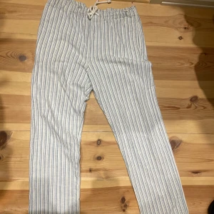 Randiga linnebyxor från Zara - Säljer ett par ljusblå och vita randiga linnebyxor från Zara i storlek M. Byxorna har elastisk midja med snörning, raka ben och två bakfickor. Perfekta för chill dagar och sommarhäng. Jag är 183 och de sitter perfekt tycker jag! 