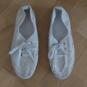 Vita tygsneakers med broderade blommor - Söta vita sneakers i tyg med broderade blommor och snörning framtill. Dom är I begagnad skick men har ändå lite kvar att ge tycker jag, se bild. Från rök och djurfritt hem