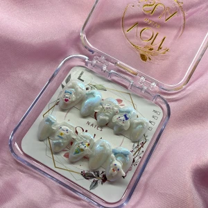 DreamBun (L);Short Almond - Supergulliga gelé press on-naglar i pärlvit med skimrande finish och 3D Cinnamoroll-motiv. Naglarna är mandelformade och dekorerade med blå rosetter och söta detaljer i pastellfärger. Perfekt för dig som vill ha unika och lekfulla naglar med extra wow-effekt.