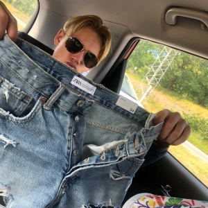 jeansshorts med slitningar - Säljer ett par ljusblå jeansshorts från Zara med råa kanter och slitningar   Helt nya