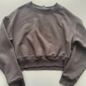Svart croppad sweatshirt från Monki - En svart croppad sweatshirt från Monki i mjuk bomullsblandning. Tröjan har rund halsringning, långa ärmar och bred mudd vid midjan och ärmsluten. Enkel och clean design som är lätt att matcha med jeans eller kjol.
