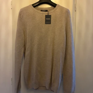 Beige stickad tröja från Dressmann - Säljer en stilren beige stickad tröja från Dressmann i storlek M. Tröjan har rund halsringning och långa ärmar, perfekt för lager-på-lager eller som den är. Enkel och klassisk design som passar till det mesta.