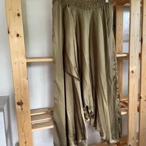 Olivgrön kjol från ZARA - Säljer en olivgrön kjol från ZARA med resår i midjan. Kjolen har en flowy och luftig känsla, då den är omlott framtill. 