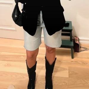 Ljusblå jeansshorts med råa kanter - Säljer ett par ljusblå jeansshorts med längre ben och råa, fransiga kanter. Klassisk femficksmodell med gylf och knapp. Perfekta för en avslappnad stil och lätt att matcha med olika toppar. Lånade bilder!!!