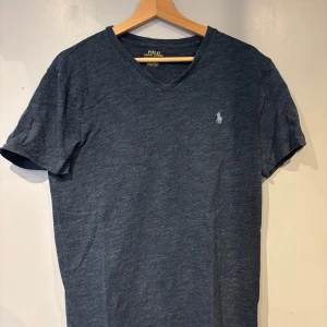 Blå v-ringad t-shirt från Polo Ralph Lauren - Mörkblå v-ringad t-shirt från Polo Ralph Lauren med broderad logga på bröstet. Slim fit passform och korta ärmar. Perfekt för en stilren och avslappnad look.