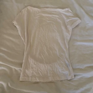 Vit kortärmad topp med öppen rygg - Säljer en vit topp med korta ärmar och öppen rygg. Toppen är i ett tunt och mjukt material, perfekt för varma dagar eller lager-på-lager. Enkel och stilren design som passar till mycket.