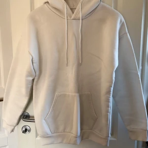 Vit hoodie med ficka - Säljer en enkel och stilren vit hoodie med huva och dragsnören. Tröjan har en stor magficka och långa ärmar i storlek s 🤍