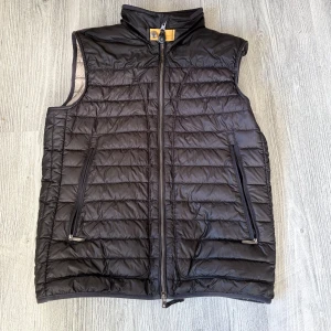 Svart dunväst från Parajumpers - Snygg svart dunväst från Parajumpers, modell Day Tripper. Västen har quiltad design, hög krage och dragkedja framtill samt två fickor med dragkedja. Perfekt för lager-på-lager och stilren look.