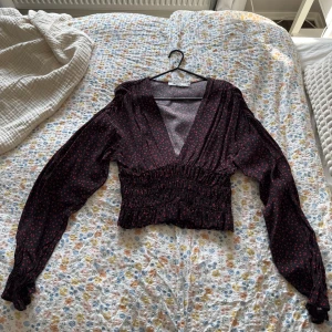 V-ringad blus  - Jättesöt blommig kort blus med djup v-ringning! Skönt luftigt material. Scrunch i axlar och midja/mage. Endast använd 1 gång. 10/10 i skick. Skicka prisförslag!