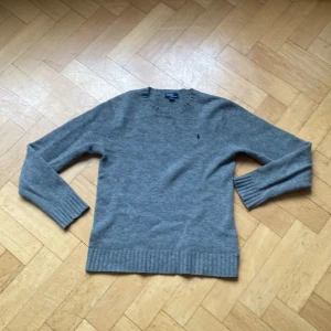 Grå ulltröja från Polo Ralph Lauren - Jag säljer härmed en grå tröja från Polo Ralph Lauren i 100%. Storleken är XL i barnstorlekar men passar XS/S i vuxenstorlekar