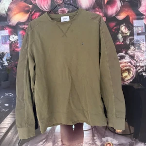 Olivgrön tröja från Dondup - Säljer en stilren olivgrön tröja från Dondup. Tröjan har långa ärmar och en diskret broderad detalj på bröstet. Perfekt för en avslappnad look.