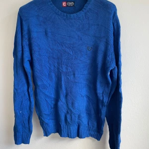 Blå stickad tröja från Chaps - Säljer en snygg blå stickad tröja från Chaps. Tröjan har en rund halsringning och långa ärmar. Perfekt för kyligare dagar och ger en stilren look. Passar bra till både jeans och chinos.