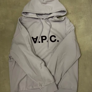 APC Hoodie - Säljer nu denna apc hoodie då den var för stor. Köpte från CETTIRE och har bara används 1 gång. Den är rosa/lila med röd text skriv om du vill ha fler bilder.