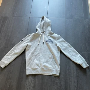 Grå hoodie från Superdry - En helt ny hoodie från superdry, aldrig använt den. Säljer då den ör får liten.