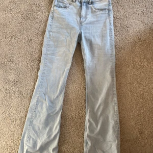 Ljusblå jeans med bootcut - Snygga ljusblå jeans med bootcut-stil och fransade kanter. De har en klassisk femficksdesign och är perfekta för en avslappnad look. Passar bra till en enkel topp eller tröja. Dessa är köpt på H&M divided. Ställ gärna frågor om ni undrar något!