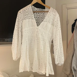 Vit klänning från Zara - Säljer en vit klänning från Zara med v-ringning och broderade detaljer. Perfekt till studenten eller andra somriga tillfällen. Klänningen är köpt på Vinted men i bra skick!