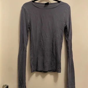 Grå långärmad topp från Gina Tricot - Säljer en stilren grå långärmad topp från Gina Tricot i storlek XS. Perfekt för lager-på-lager eller som den är. Enkel och mångsidig design som passar till det mesta. Hör av dig vid intresse! 💬 den har slits längst ner på armarna den är i jätte fint skick 