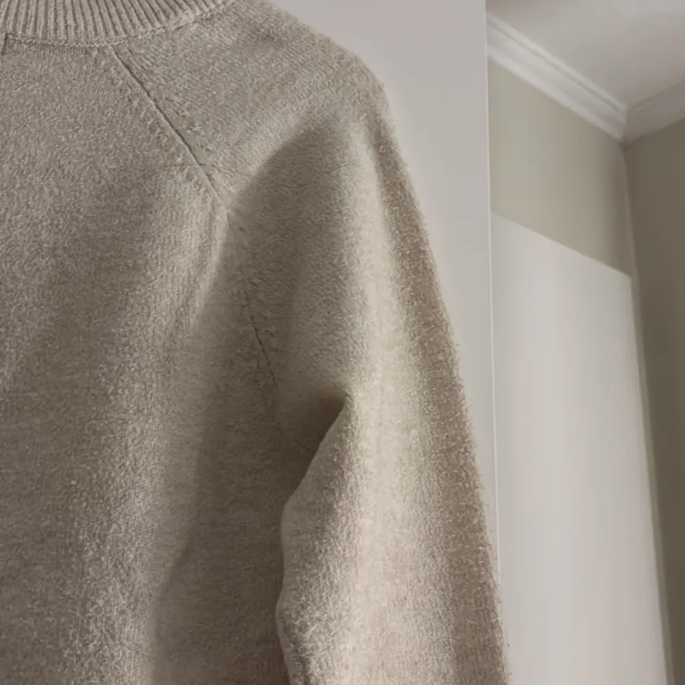 Säljer en mysig beige stickad tröja från Vero Moda. Tröjan har en klassisk design med långa ärmar och ribbade muddar vid ärmslut och nederkant. Perfekt för kyliga dagar!. Neuletakit & Villapaidat.
