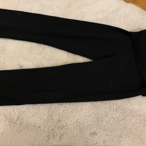 Ett svart sett från Gina tricot - Säljer ett ett svart sett med en tröja och mjukisbyxor från Gina tricot. Byxorna har en ribbad mudd vid bensluten och är tillverkade i ett mjukt material för extra komfort. Tröjan är gjord i samma material och är perfekta för en avslappnad stil.