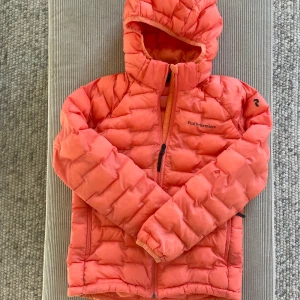 Dunjacka från Peak Performance - Dunjacka från Peak Performance, Argon light i orange storlek 150. Är i bra skick förutom ett hål på en arm, se bild, därav priset. Nypris 1699 kr.