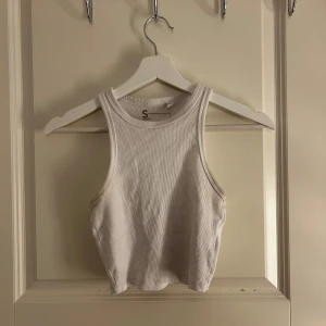 Vit ribbad linnetopp - Säljer en stilren vit ribbad linnetopp med en croppad passform. Perfekt för varma dagar eller som ett lager under en jacka. Enkel och mångsidig design som passar till det mesta. 🕶️