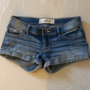 Blå jeansshorts från Hollister - Säljer ett par snygga blå jeansshorts från Hollister. De har en klassisk femficksdesign och är lågmidjade med en knapp och dragkedja framtill. Perfekta för varma sommardagar! 💙storlek 23, passar mig perfekt som har storlek 32,34 i byxor!🥰