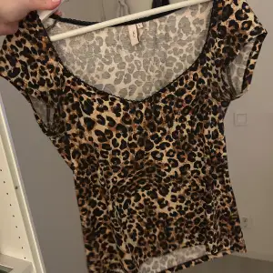 Säljer en leopardmönstrad topp med korta ärmar. Toppen har en rund halsringning och är gjord i ett lätt och luftigt material. Perfekt för att ge din outfit en vild touch! 🐆