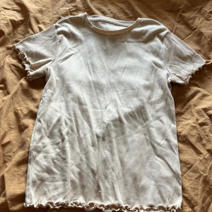 Rosa ribbad t-shirt med volangdetaljer - Säljer en söt rosa ribbad t-shirt med volangdetaljer vid ärmslut och nederkant. Perfekt för en avslappnad stil. Passar till allt och är superbekväm!