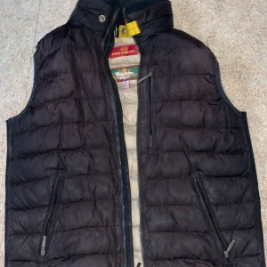 Svart dunväst från Parajumpers - Snygg svart dunväst från Parajumpers med dragkedja och två praktiska fickor framtill. Perfekt för kyligare dagar och ger en stilren look. Västen har en quiltad design och är idealisk för både höst och vår. Hör av er vid flera frågor!!