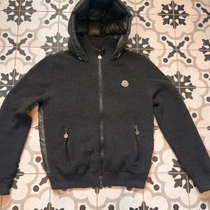 Grön cardigan från Moncler - Säljer en snygg svart stickad jacka från Moncler med quiltad baksida och med luva. Väldigt litet se bild 5. Självklart äkta. 