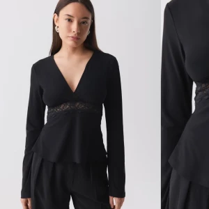 Svart långärmad blus med spetsdetalj - Elegant svart blus med v-ringning och spetsdetalj i midjan. Långärmad design som ger en stilren look. Perfekt för en chic och sofistikerad stil. 