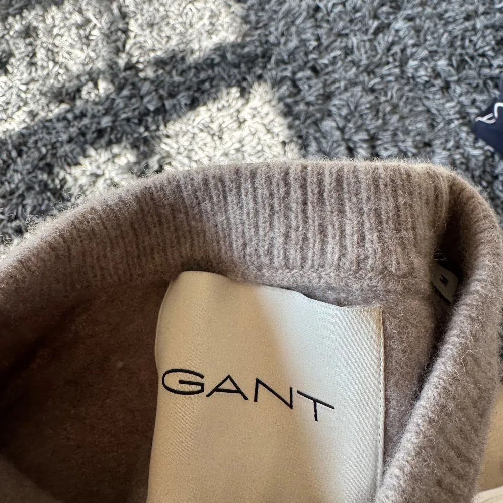 Säljer en stilren beige tröja från GANT. Perfekt för en avslappnad och snygg look. Tröjan har långa ärmar och en klassisk rund halsringning. Den har krympt i tvätten, de står M i den men skulle säga ett den är mer åt S/xs hållet nu. Neuletakit & Villapaidat.