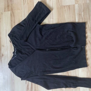 Svart kofta från KappAhl - Säljer en klassisk svart kofta från KappAhl i storlek S. Koftan har långa ärmar och knappar framtill. Perfekt för lager-på-lager och enkel att matcha med olika outfits.