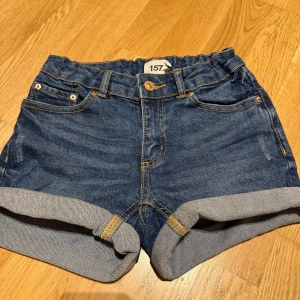 Blå jeansshorts från lager 157💙 - Snygga blå jeansshorts från lager 157 med elastisk midja och uppvikta benslut. Shortsen har klassiska fem fickor och en knapp framtill.⭐️