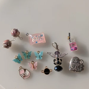 Blandade berlocker och hängen - Säljer ett set med olika berlocker och hängen. Inkluderar fjärilar i blått och rosa, en hjärtformad berlock i silver, en svart planetberlock, och en rosa flaska med pärlor. Perfekt för att skapa egna smycken eller som dekorationer. Vissa är handgjorda säljer allt på bilden för 28 kr. Man kan köpa styckvis meddela i sådana fall. Vissa har rostat lite grann men det märks inte så tydligt enligt mig.