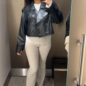 Svart croppad skinnjacka - Säljer en svart, croppad skinnjacka med dubbelknäppning. 