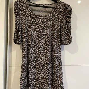 Leopardmönstrad blus - Snygg blus med leopardmönster i svart och beige. Blusen har rund halsringning och korta puffärmar som ger en cool och trendig vibe. 