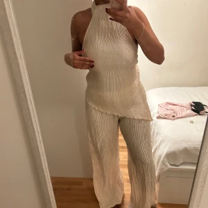 Champagne sett  - Säljer ett sett från Zara i färgen Champagne shimmer. Byxorna efterliknar linnebyxor designen och toppen är en high neck top men en öppen rygg och lite längre på ena sidan. Har använt settet ett par gånger. Tyvärr är änden av byxorna lite missfärgade eftersom de är för långa för mig blivit smutsiga, och vid tvätt blivit lite missfärgade. Dock är det inte jätte synligt. Går även att köpa ena av plaggen, antigen toppen eller byxorna. Tillsammans säljer jag settet för 200kr, separat för 150kr styck