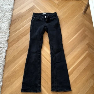 Svarta bootcut jeans med fickdetaljer från gina  - Snygga svarta jeans med bootcut passform och coola fickor med lock och knappar bak. Klassisk femficksmodell med dragkedja och knapp framtill. Perfekta för dig som gillar en retroinspirerad look med lite utsvängda ben.