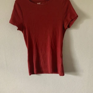 Röd t-shirt från VC - En enkel och stilren röd t-shirt från VC med rund hals och korta ärmar. T-shirten har en klassisk passform och är gjord i mjuk bomull som känns skön mot huden. Perfekt för dig som gillar minimalistisk stil och vill ha en basic i garderoben.