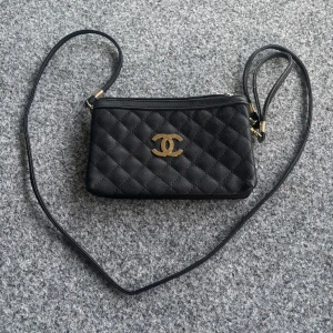 Svart quiltad axelväska  - Säljer en svart quiltad axelväska  med klassiskt guldigt spänne framtill. Väskan har smal axelrem, två stora fack med dragkedja och en mindre ficka bak. Tillverkad i skinn med lyxiga gulddetaljer och brun insida.