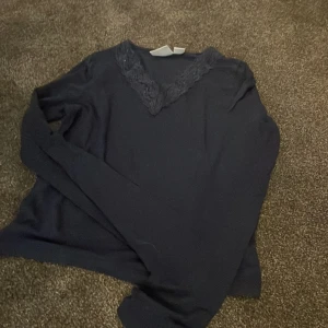 Mörkblå långärmad tröja Gina Tricot - Supersnygg mörkblå långärmad tröja från Gina Tricot med v-ringning och spetsdetalj vid halsen. Perfekt för dig som gillar stilrena plagg med en twist. Skön passform och enkel att matcha med dina favoritjeans eller kjol.