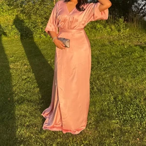 Maxiklänning By Malina - Superfin ljusrosa långklänning i glansigt satinliknande material. Klänningen har v-ringning, vida trekvartsärmar och är omlottsklänning. Perfekt för bal eller sommarens speciella tillfällen. .