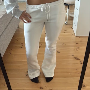 Vita lågmidjade mjukisbyxor med snörning - Säljer ett par vita lågmidjade mjukisbyxor med bootcut-snitt och snörning i midjan från Nitted. Byxorna har normal passform och är tillverkade i mjukt bomullsmaterial. Perfekta för en chill och avslappnad stil. 