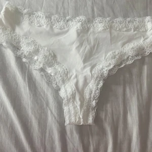 Vit och svart brasilian underkläder med spets - Två snygga brazilian underkläder i klassisk vit och svart färg. Båda har en feminin spetskant runt hela midjan och benöppningarna. Tunnt och bekvämt material. Säljs tillsammans! OBS: absolut helt oanvända!