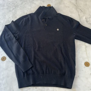 Mörkblå polotröja Morris M - Snygg mörkblå polotröja från Morris i 100% merinoull. Tröjan har klassisk krage med två knappar och ett litet broderat emblem på bröstet. Perfekt för dig som gillar stilrena och bekväma plagg med premiumkänsla.