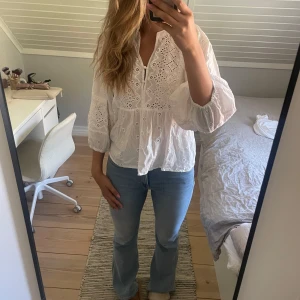 Vit broderad blus med vida ärmar - Superfin vit blus, broderade detaljer och hålmönster. Snygg att styla med jeans eller kjol.