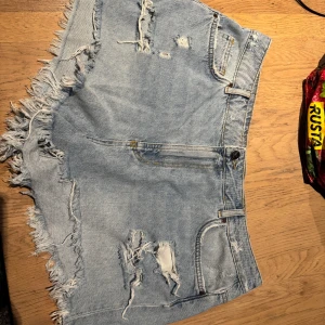 Ljusa jeansshorts från Never Denim - Snygga ljusblå jeansshorts från Never Denim med fransig kant och slitna detaljer både fram och bak. Loose fit som ger skön vibe. Oanvända 🫶🏻 är xl i storleken men är små, så mer som en L eller stor M